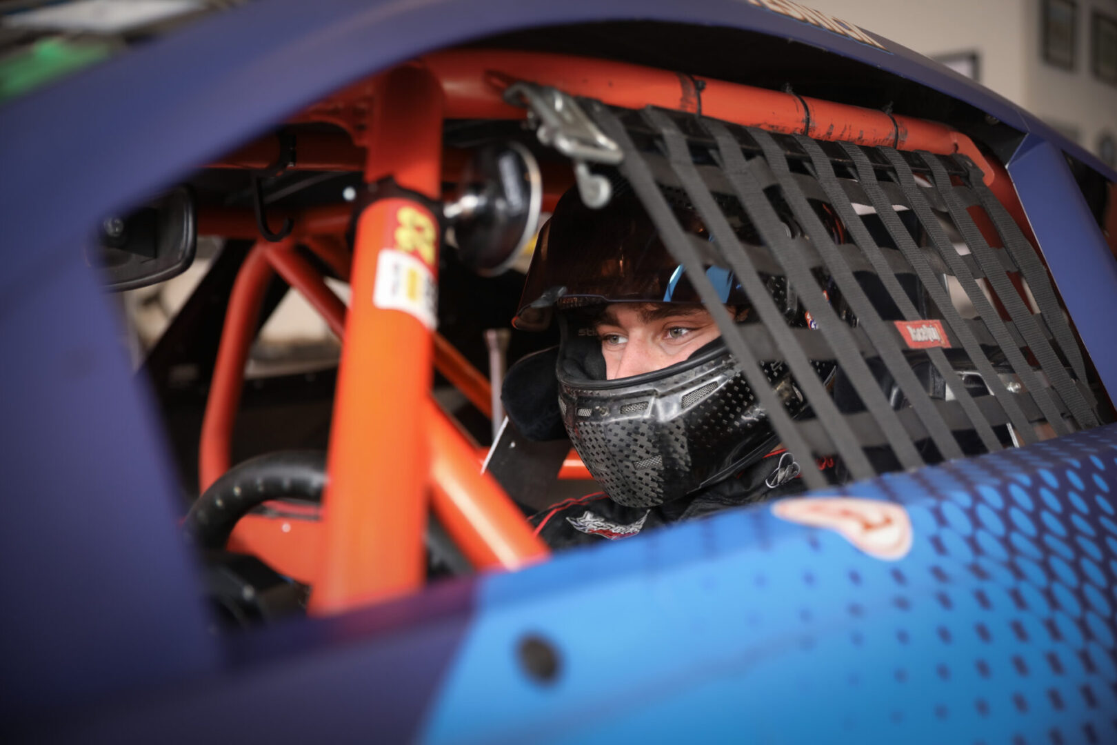 Man inside a blue race car with rolling cage